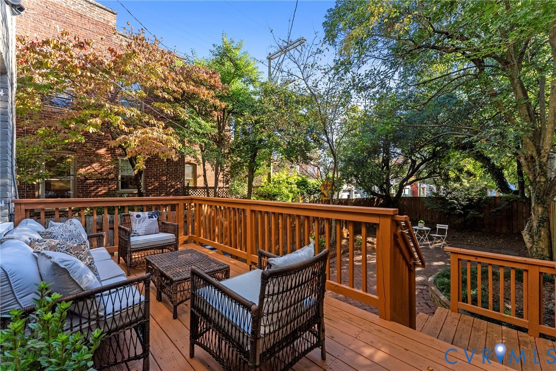 Multi-level wood deck featuring built-in railings, steps, and mature tree canopy overhead