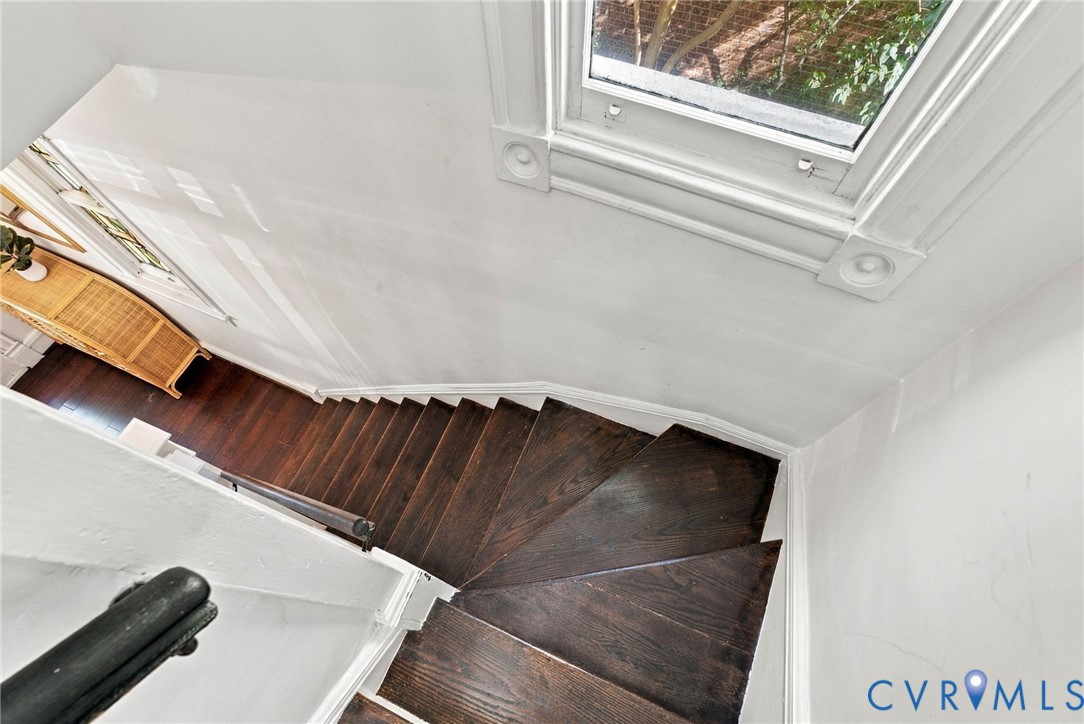 Staircase featuring dark-stained wood treads, white wall paneling, detailed window casing with rosette corner blocks, and a simple dark railing