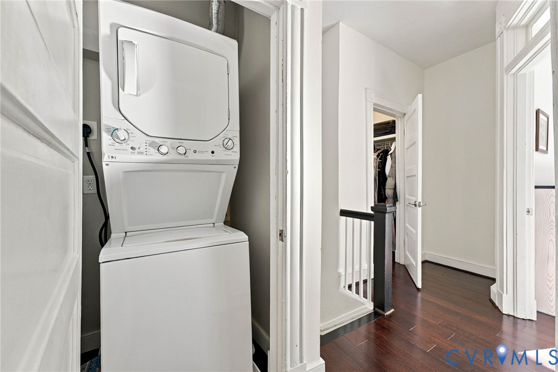 Stacked laundry center featuring a white finish, dark wood-finish flooring, and multi-panel interior doors