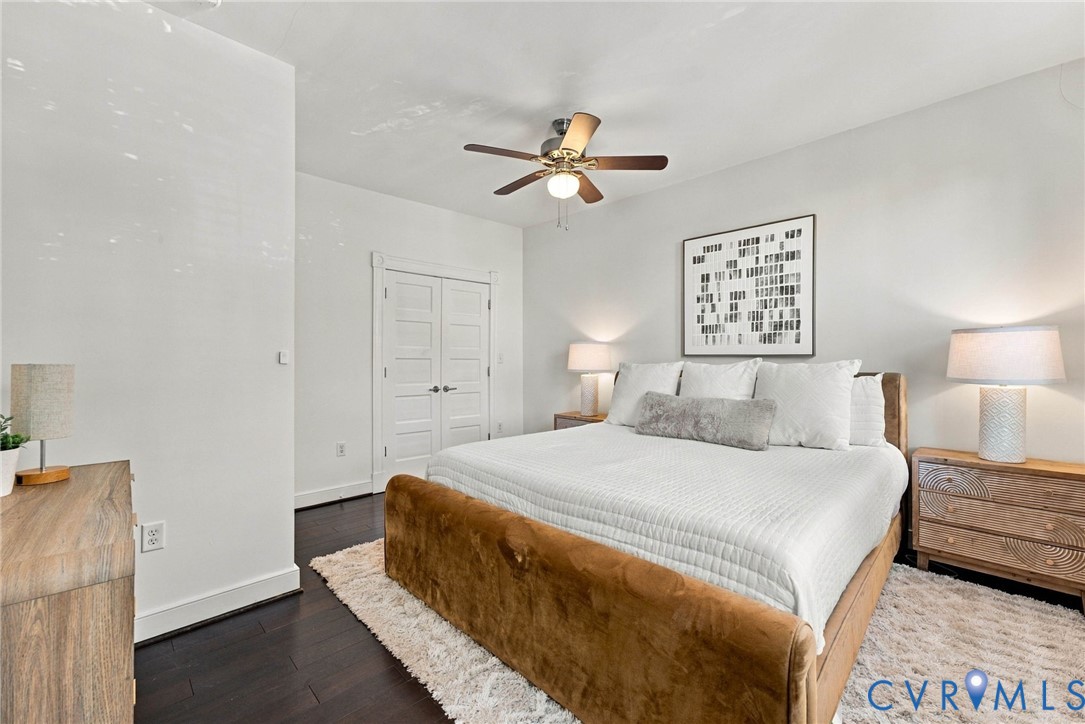 Dark-toned wood-finish flooring, white five-panel double doors, and a central ceiling fan with integrated lighting