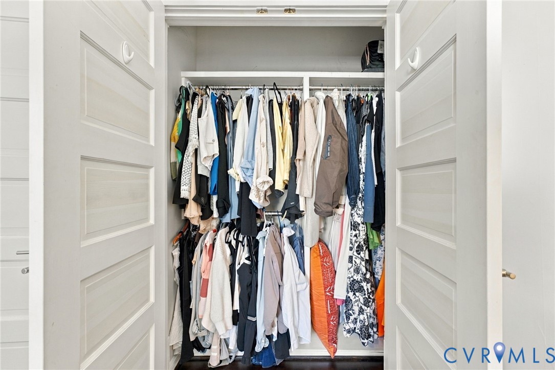 Storage closet featuring dual shaker-style doors, integrated hanging rods, and built-in upper shelving