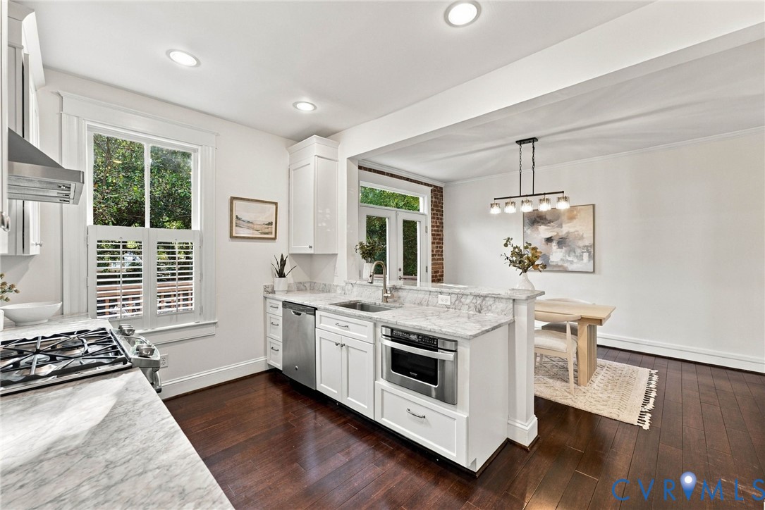 Kitchen featuring white shaker-style cabinetry, stone countertops, stainless steel appliances, dark wood-finish flooring, and recessed lighting