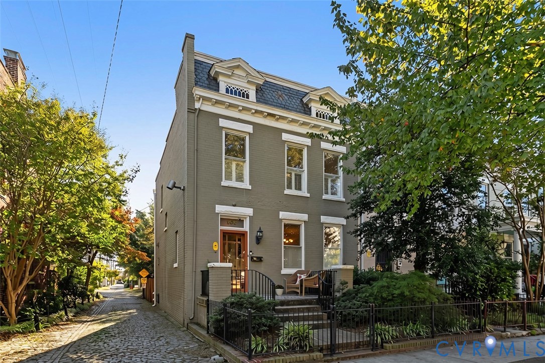 Three-story brick exterior featuring a mansard roofline, dormer windows, decorative cornice detailing, and a front entry with wrought-iron railing