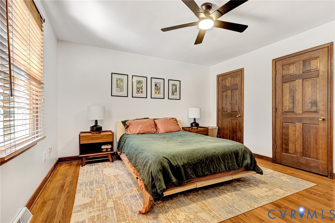 Wood-finish flooring, multi-pane wood doors, and a ceiling fan with integrated lighting