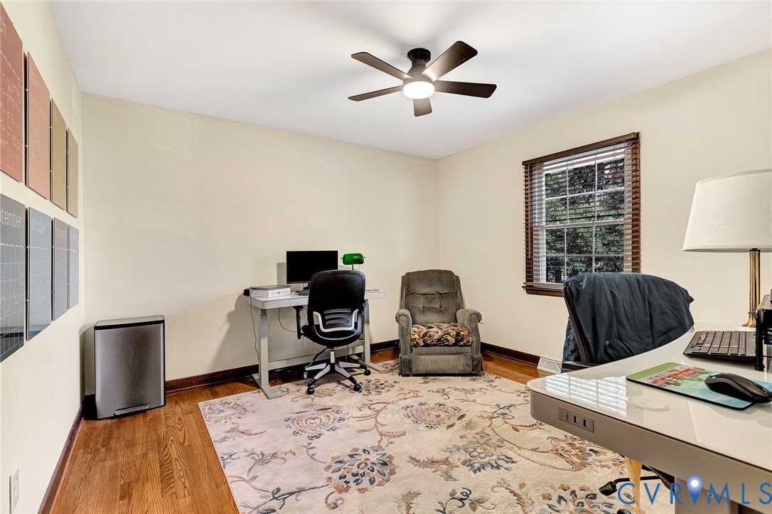Wood-finish flooring, multi-pane window with wood-slat blinds, and overhead ceiling fan with integrated lighting
