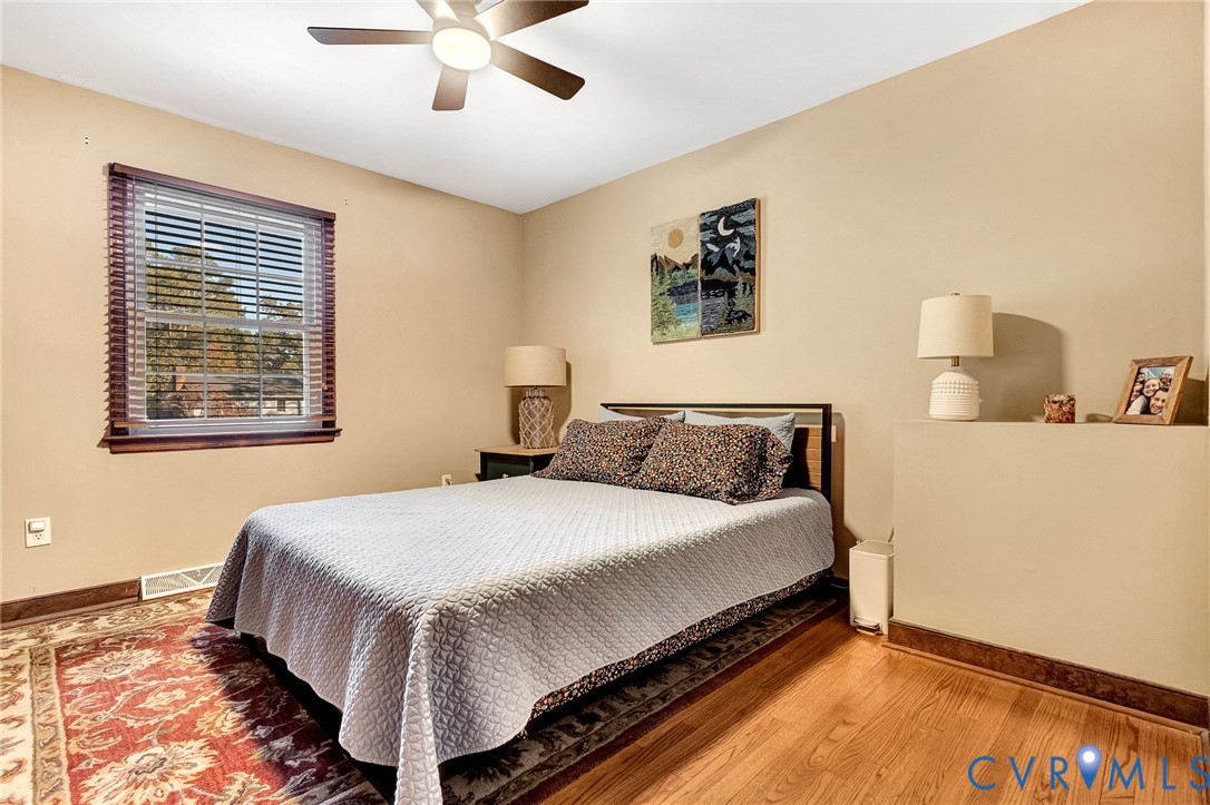 Room featuring wood-finish flooring, a multi-pane window with blinds, and a ceiling fan with integrated lighting