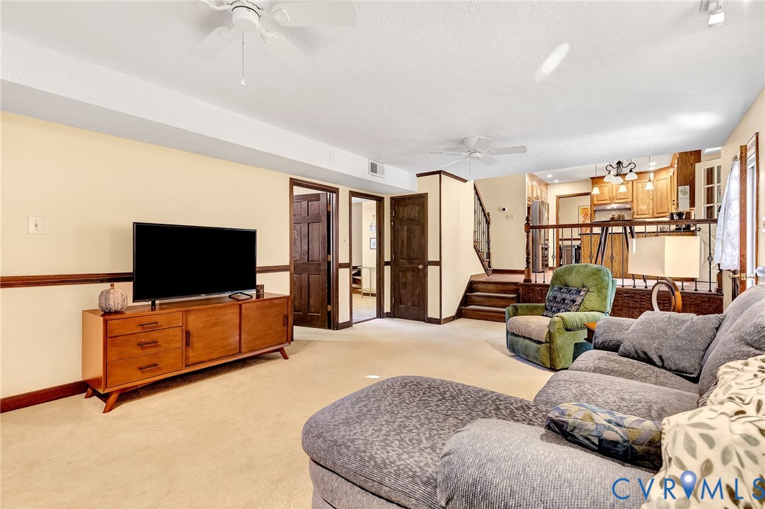 Spacious interior featuring neutral carpeting, multi-panel wood doors, chair rail molding, and a tiered layout with decorative wood railing