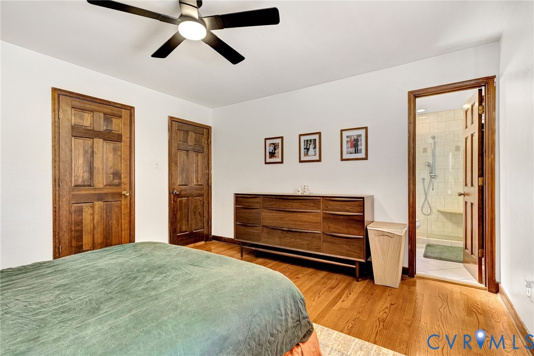 Wood-finish flooring, multi-panel wood doors, and a ceiling-mounted light fixture with fan