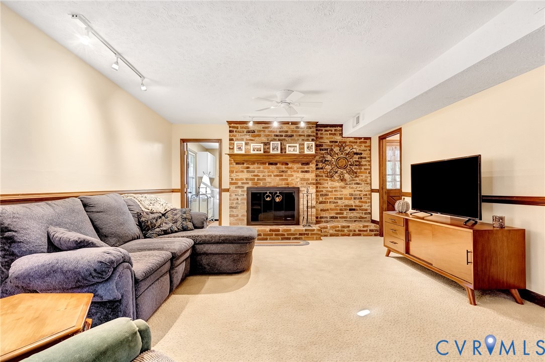Full-height brick fireplace featuring a wood mantel, raised hearth, and track lighting, complemented by chair rail molding
