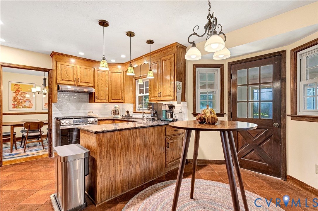 Kitchen featuring wood cabinetry, stone countertops, a tiled backsplash, tile flooring, and a multi-pane wood-finish exterior door