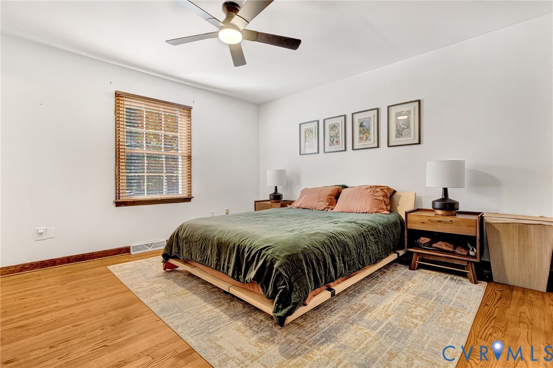 Wood-finish flooring, multi-pane window with wood-trim framing, and a ceiling-mounted light fixture with integrated fan
