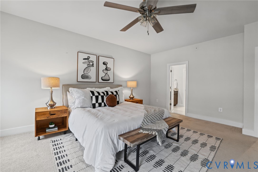 Spacious room featuring neutral carpeting, a ceiling fan with integrated lighting, and a doorway opening to a secondary room