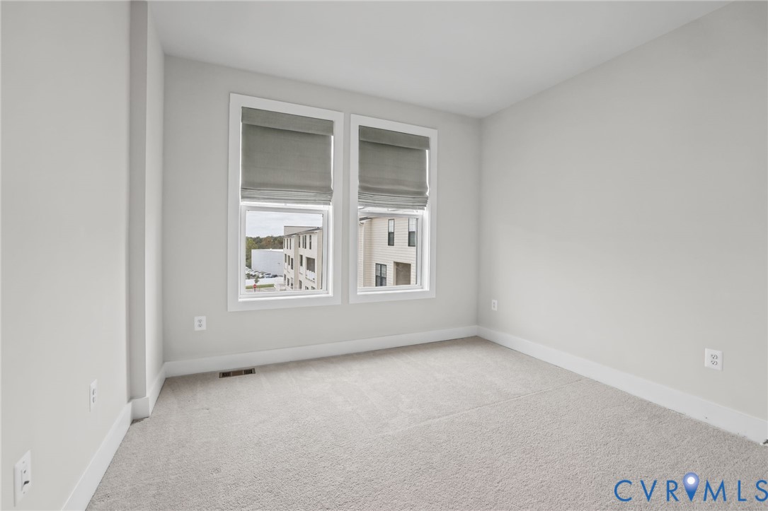 Neutral-toned room featuring wall-to-wall carpeting and dual windows with integrated shades