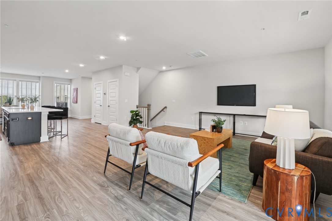 Open-concept floor plan featuring wood-finish flooring, recessed lighting, and a kitchen island with stone-style countertops