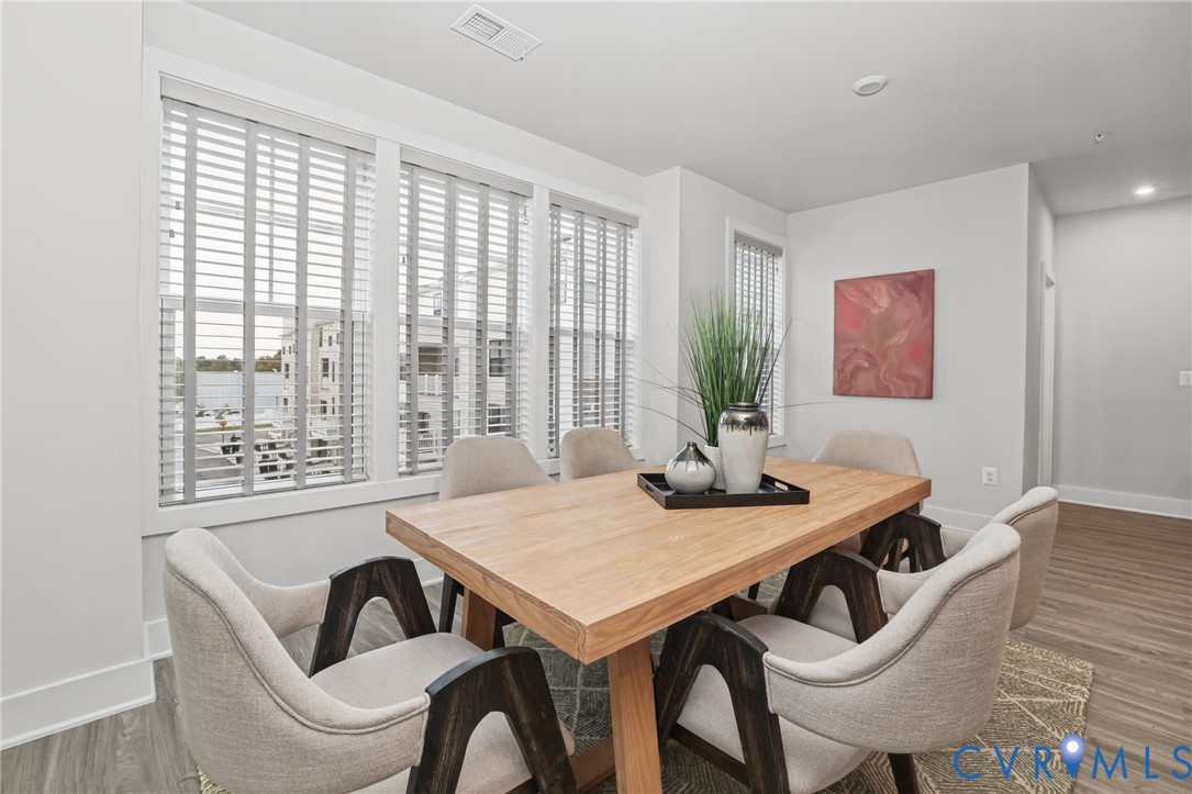 Neutral color palette with wood-finish flooring and large windows featuring horizontal blinds