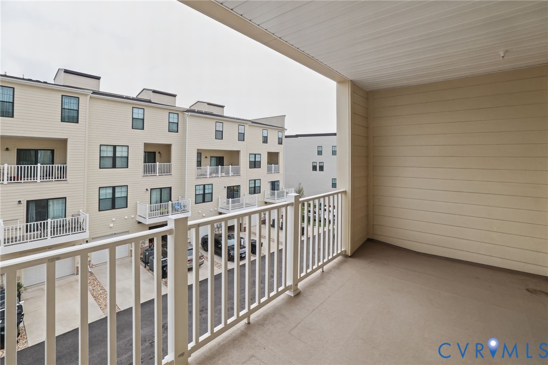 Covered balcony featuring horizontal lap siding, concrete flooring, and white railing