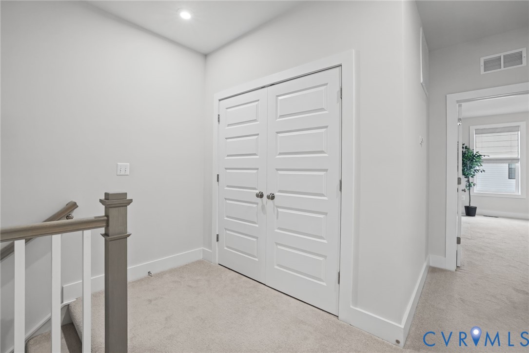 White five-panel double doors, neutral carpeting, and a wooden handrail with vertical balusters