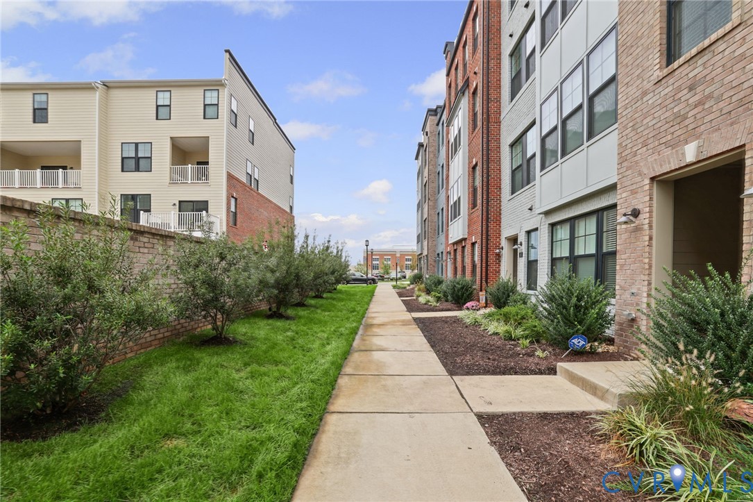 Exterior facade featuring a combination of brick and siding, concrete walkway, manicured lawn, and landscape shrubbery
