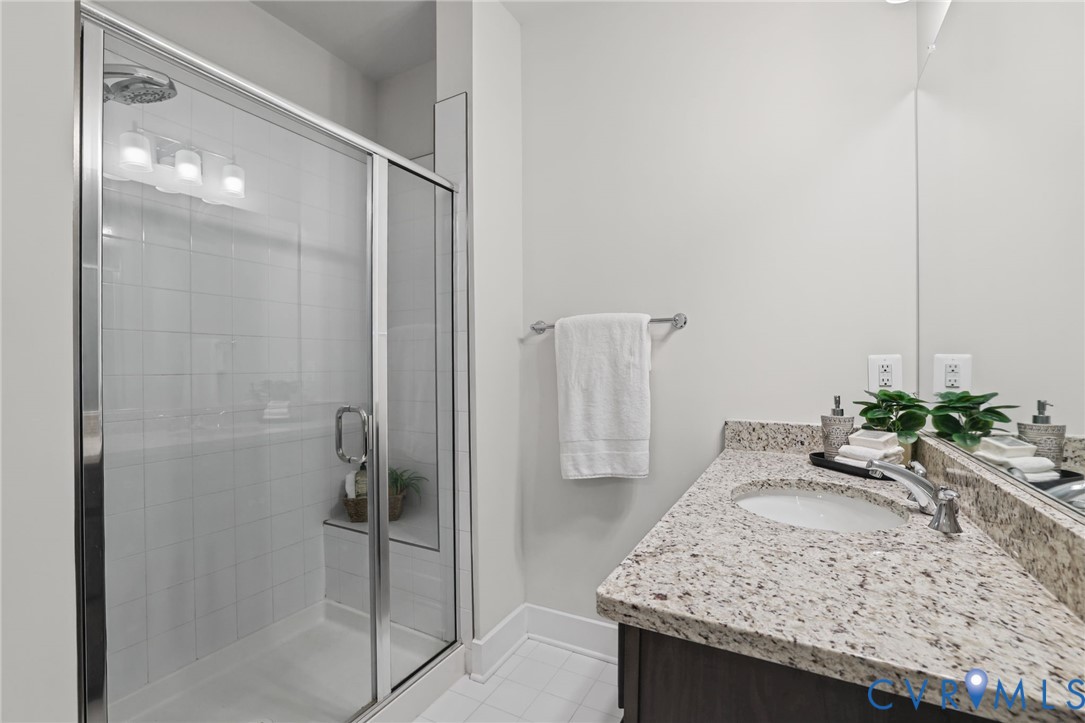 Bathroom featuring a shower with a glass enclosure and built-in bench, stone-composite countertop, undermount sink, and full-width vanity mirror