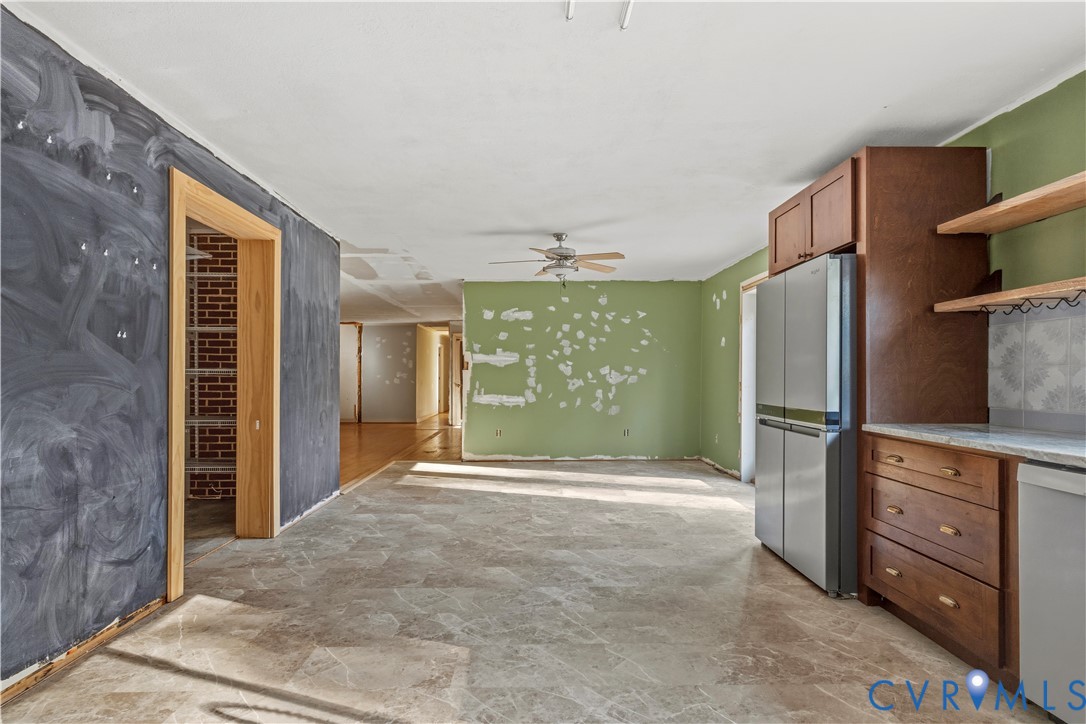 Stainless steel refrigerator, wood-finish cabinetry, built-in shelving, tiled backsplash, and wood-finish door frames