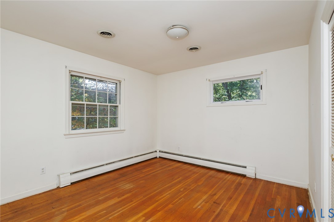 Room featuring wood-finish flooring, white walls, double-hung window, horizontal window, and flush-mount ceiling light
