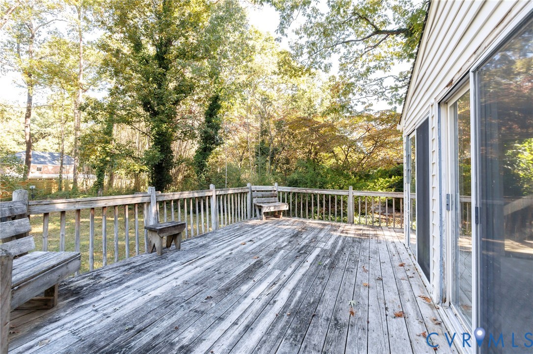 Elevated wood deck featuring integrated built-in benches, perimeter railing, and sliding glass door access