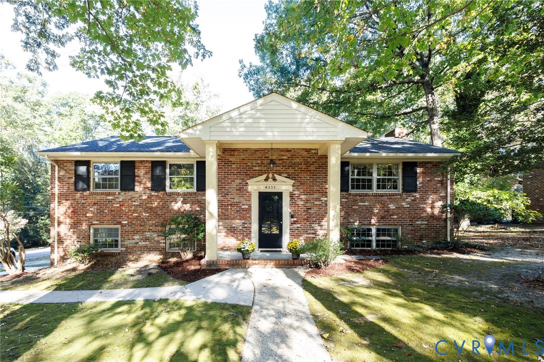 Brick exterior featuring a covered entryway with structural columns, multi-pane windows with shutters, and a front gabled roofline Brick exterior featuring a covered entryway with structural columns, multi-pane windows with shutters, and a front gabled roofline