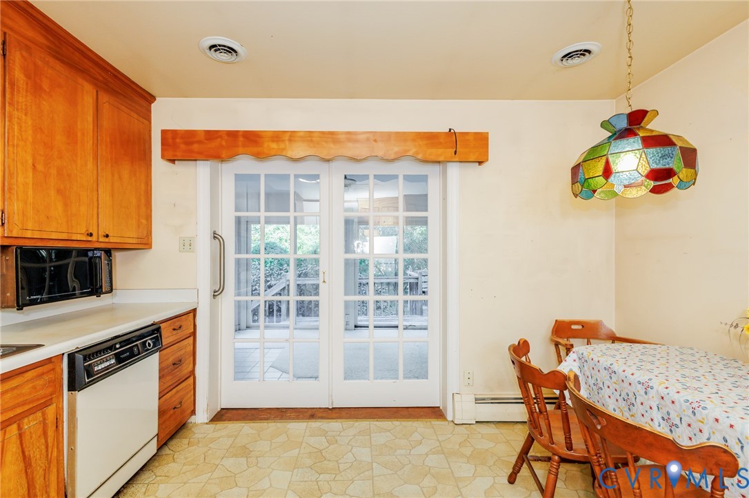 Kitchen space featuring wood cabinetry, an integrated dishwasher, dual-pane glass sliding doors, and a multi-colored stained-glass pendant light fixture