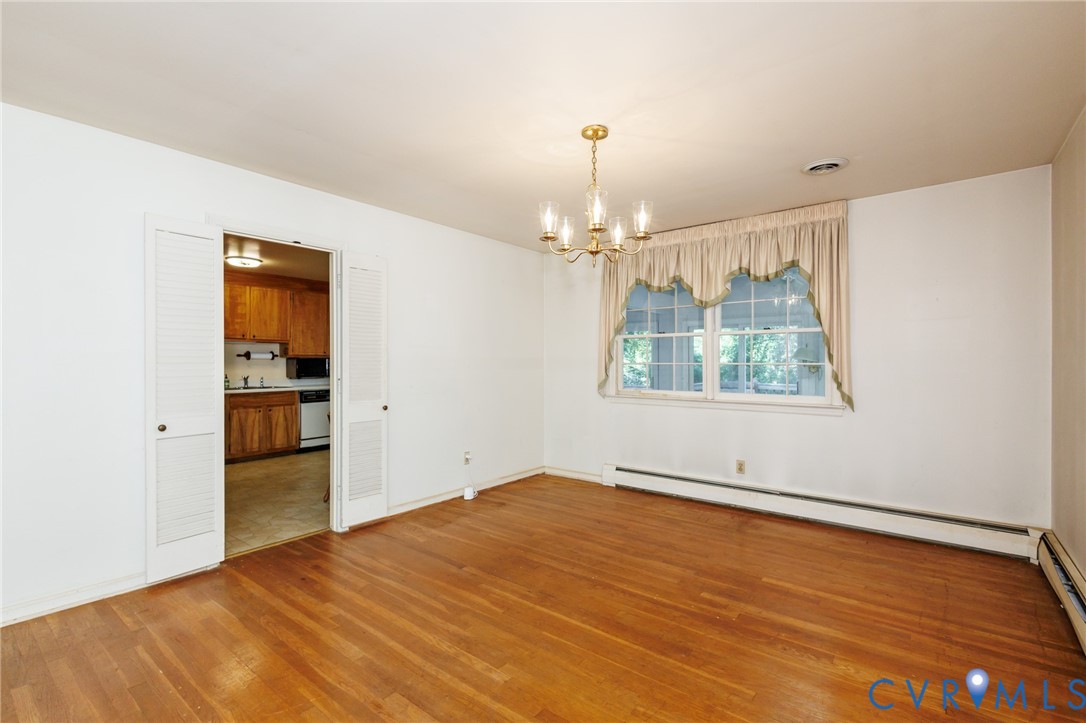 Room featuring wood-finish flooring, a multi-arm chandelier, and double louvered closet doors