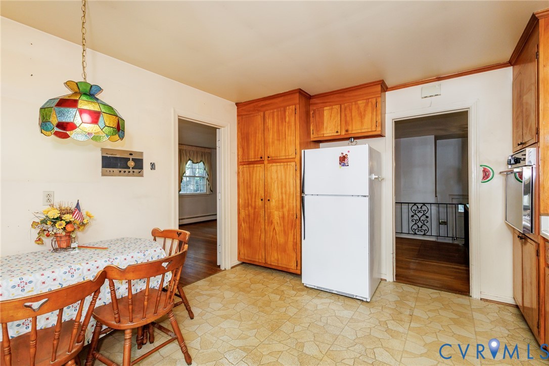 Kitchen area featuring wood cabinetry, floor-to-ceiling pantry storage, integrated wall oven, and resilient stone-pattern flooring