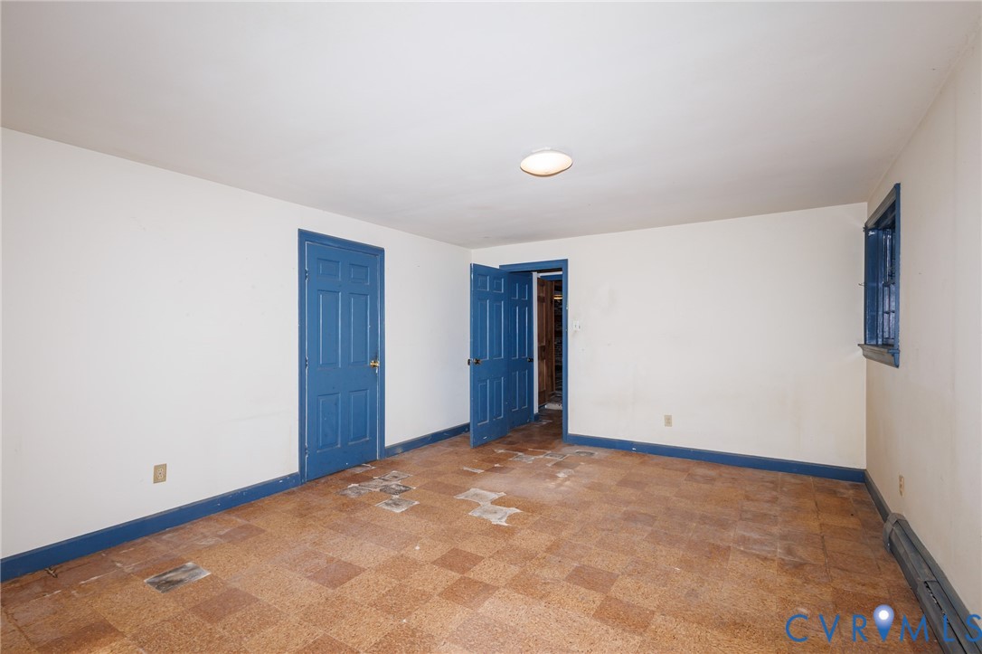 Interior room featuring checkerboard-patterned floor tiles, two blue-painted six-panel doors, and a single window with a blue-painted frame
