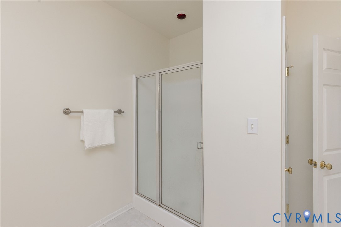 Walk-in shower featuring a framed glass enclosure, neutral wall finish, and a mounted metal towel bar