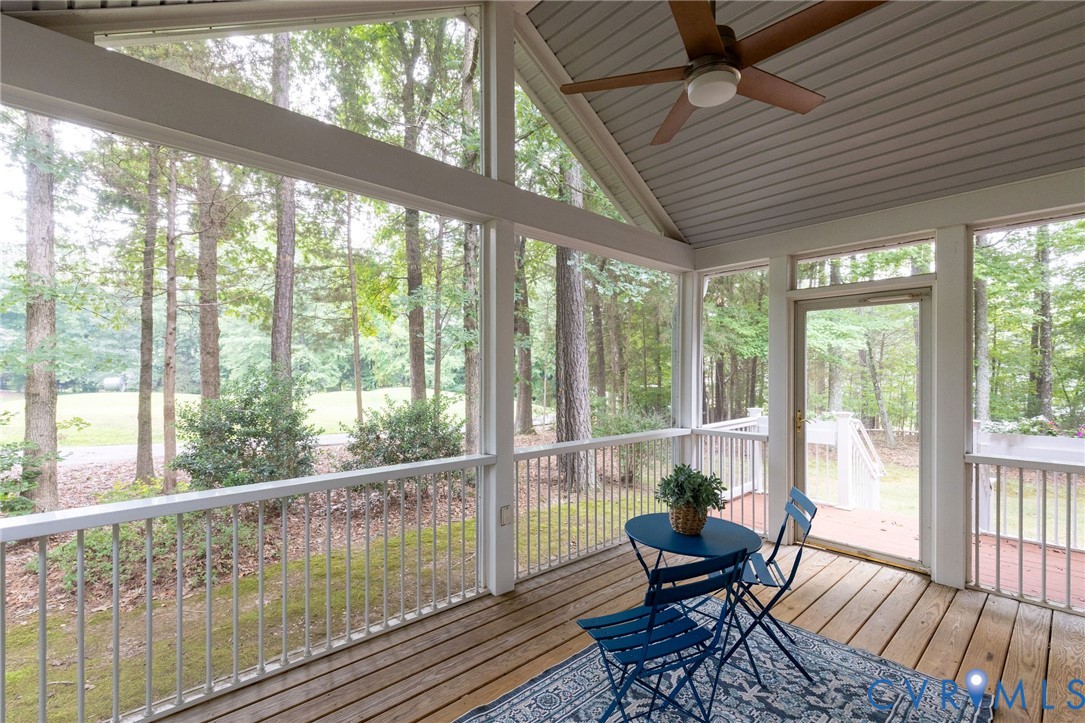 Screened-in porch featuring vaulted ceilings, wood-plank flooring, ceiling fan, and perimeter railing