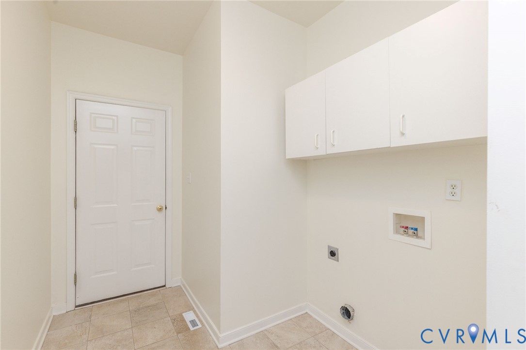 Utility area featuring tile flooring, white shaker-style wall-mounted cabinetry, and dedicated washer and dryer hookups