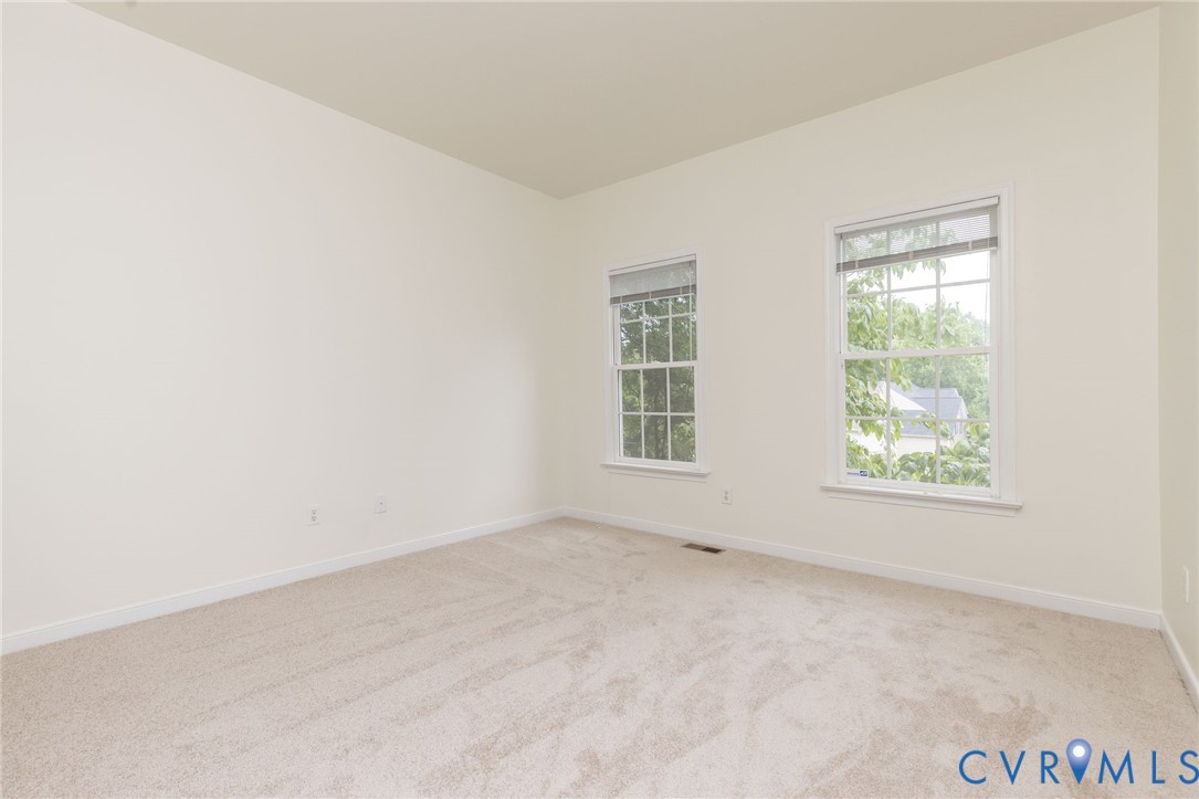Neutral-toned interior room featuring wall-to-wall carpeting and two dual-pane double-hung windows with grid muntins