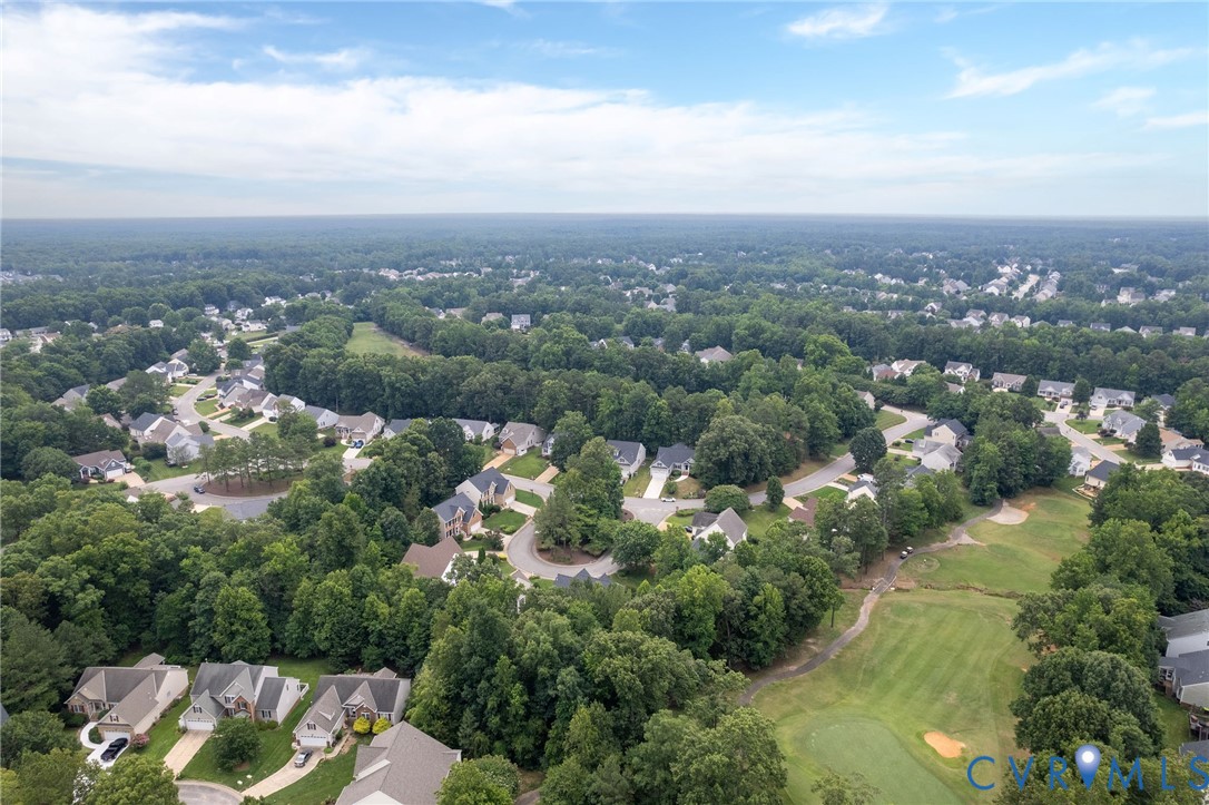 Aerial perspective featuring suburban residential streets, mature tree canopy, and proximity to a golf course