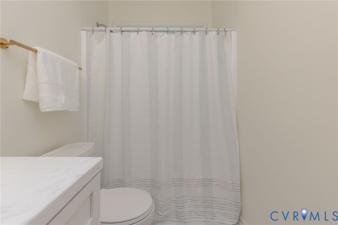 Bathroom featuring a vanity with a white countertop, gold-toned hardware, and a combination tub and shower