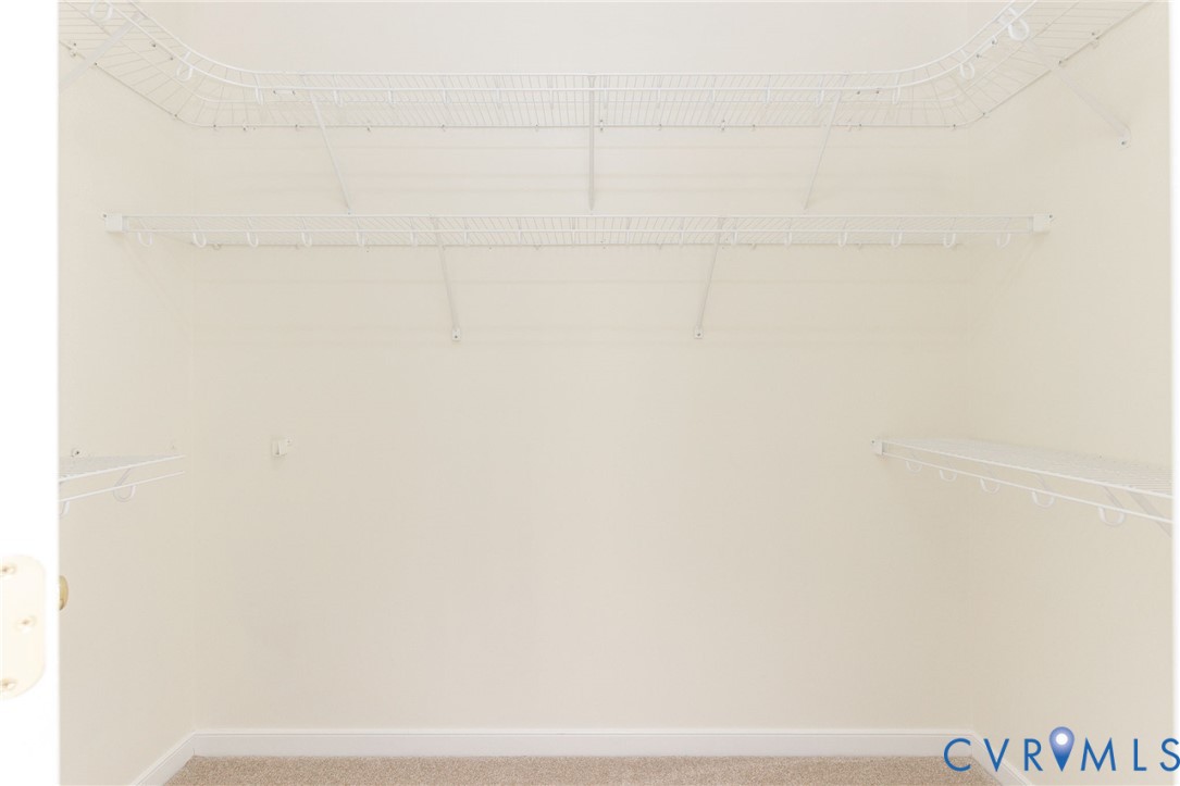 Storage area featuring multi-level white wire shelving and carpeted flooring