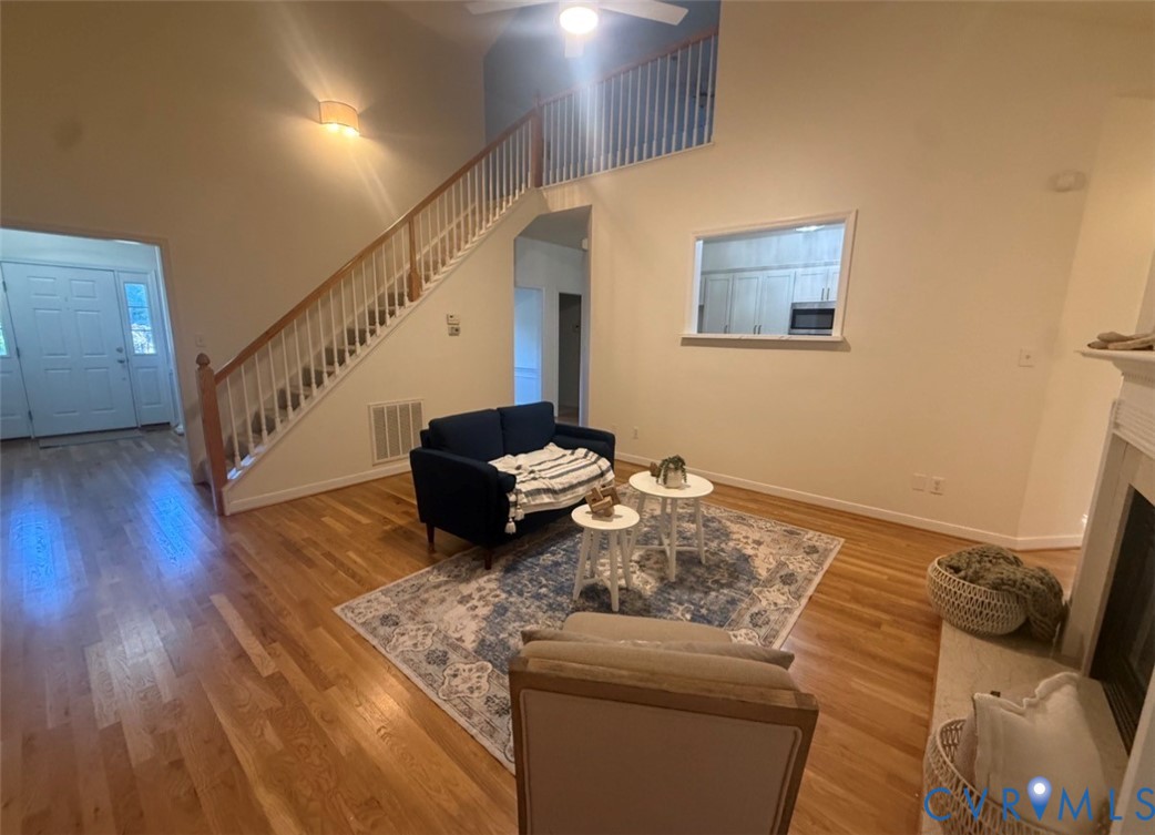 Vaulted ceilings, staircase with wooden handrail, wood-finish flooring, interior pass-through window, and fireplace surround