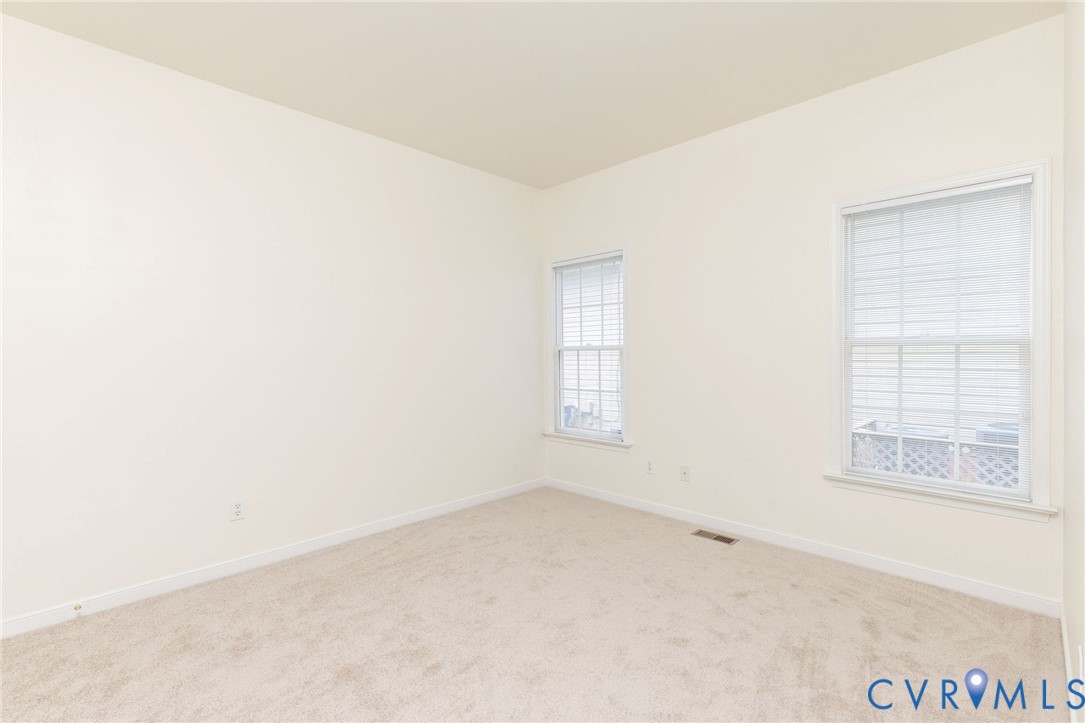 Neutral interior space featuring high ceilings, light-toned wall-to-wall carpeting, and two double-hung windows with integrated grid patterns