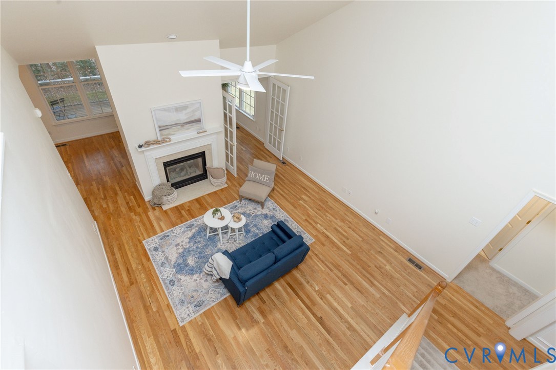 Vaulted ceilings, wood-finish flooring, fireplace with a tiered mantel, and white French doors