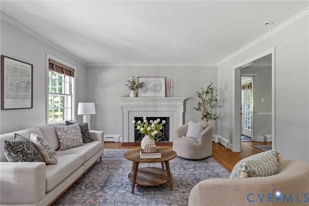 Living area featuring crown molding, wood-finish flooring, and a fireplace with a decorative mantel