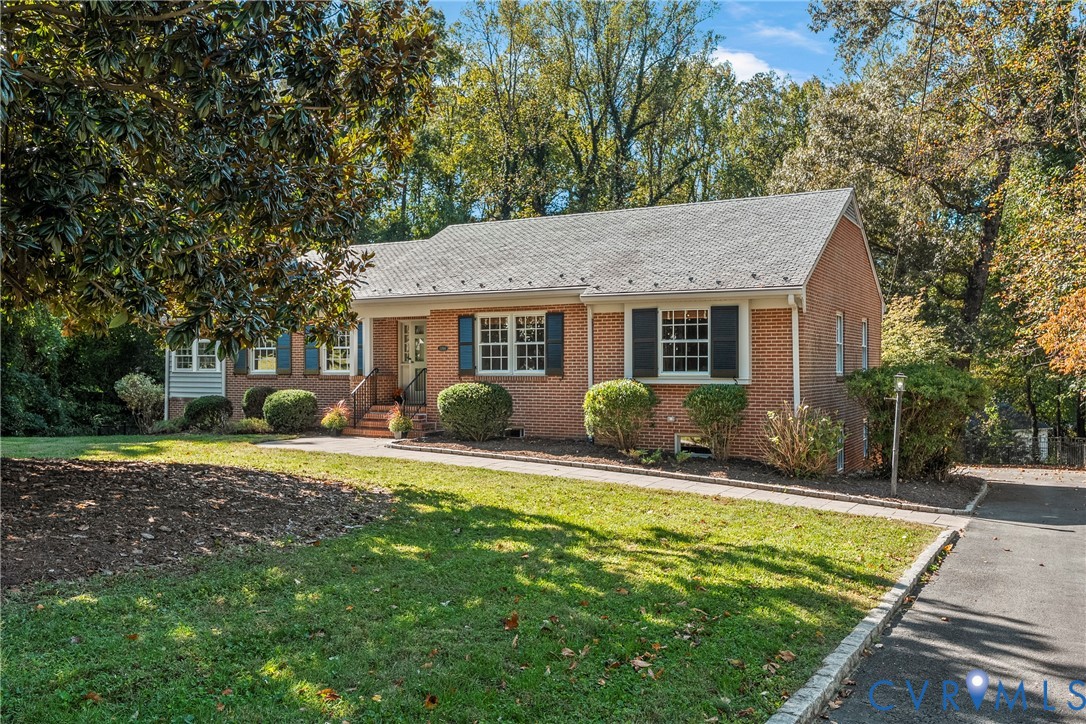 Brick exterior featuring gabled roof lines, multi-pane windows with operable shutters, and an asphalt driveway