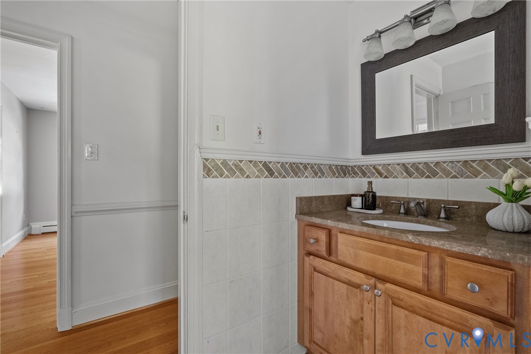 Bathroom vanity featuring a natural wood cabinet, stone countertop with an integrated oval sink, and a multi-light fixture