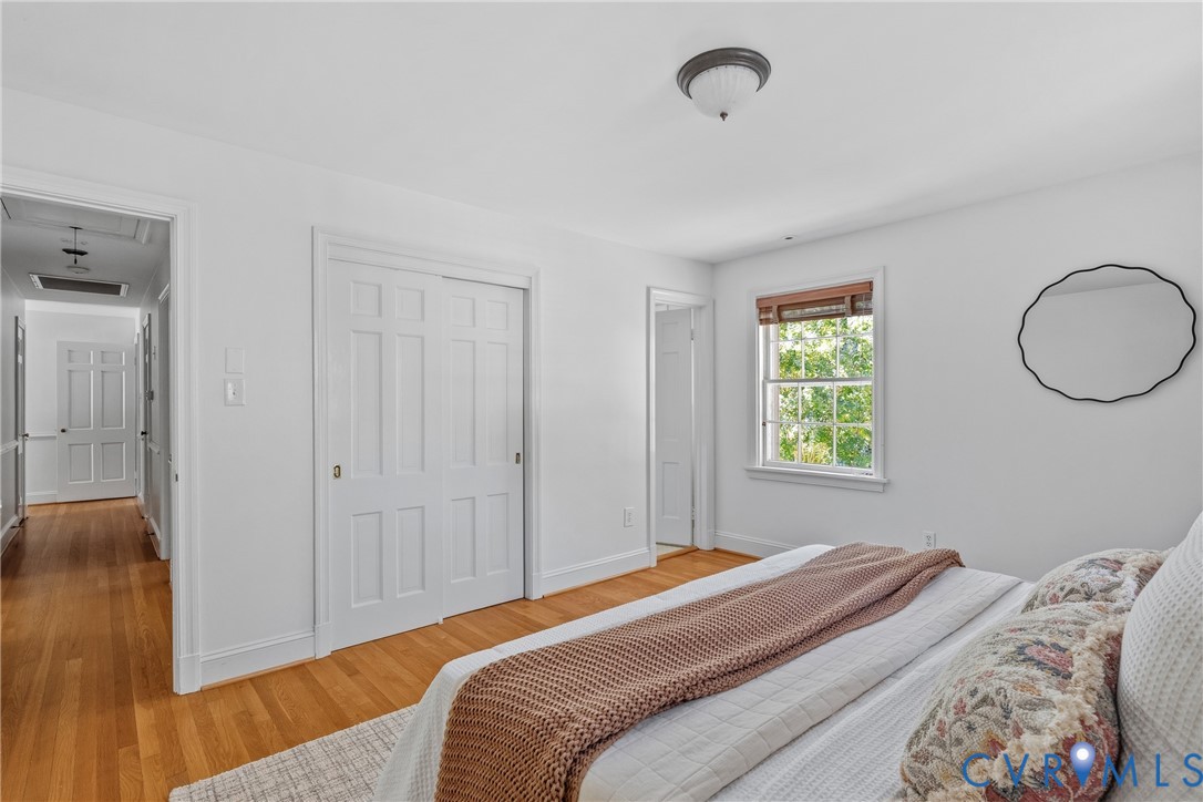 Interior space featuring wood-finish flooring, white paneled closet doors, and a double-hung window with wood-trim finish