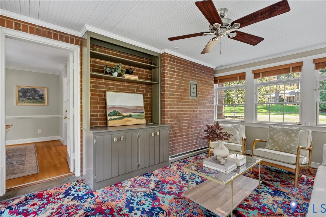 Exposed brick accent wall with built-in shelving, tongue-and-groove ceiling, multi-pane windows, and wooden-blade ceiling fan
