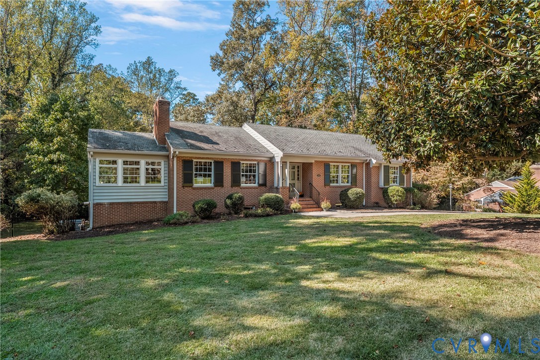 Single-story brick exterior featuring a multi-gabled roofline, functional shutters, an exterior chimney, and a sprawling front lawn