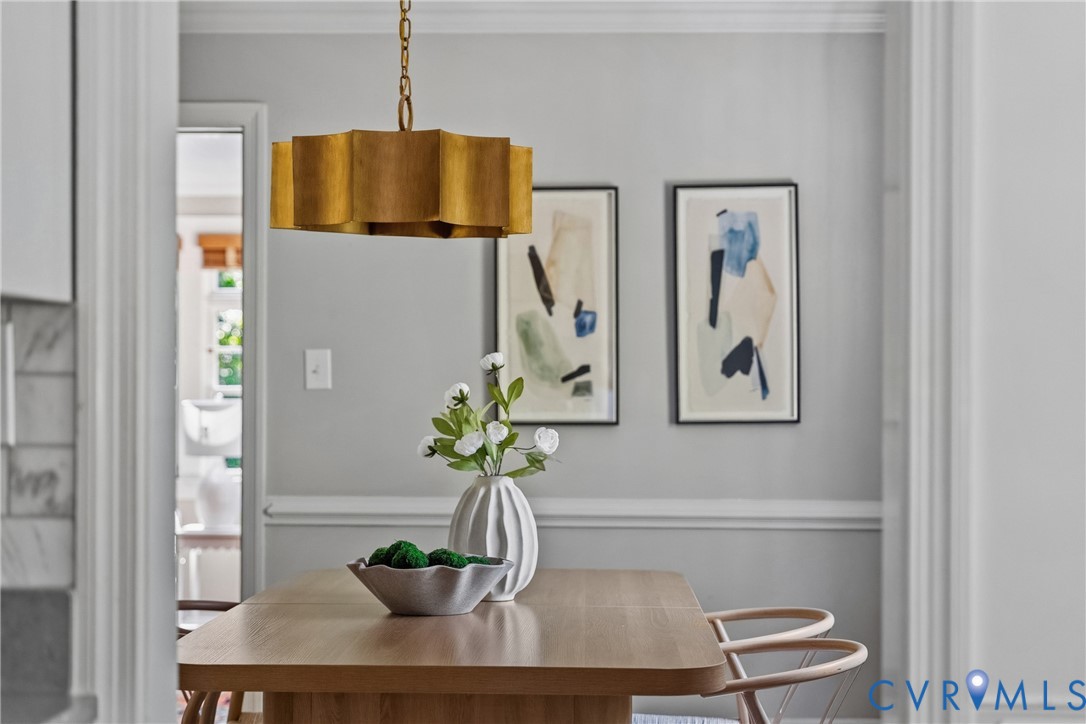 Gold-tone metal drum pendant light with a scalloped profile, crisp chair rail molding, and neutral interior wall paint