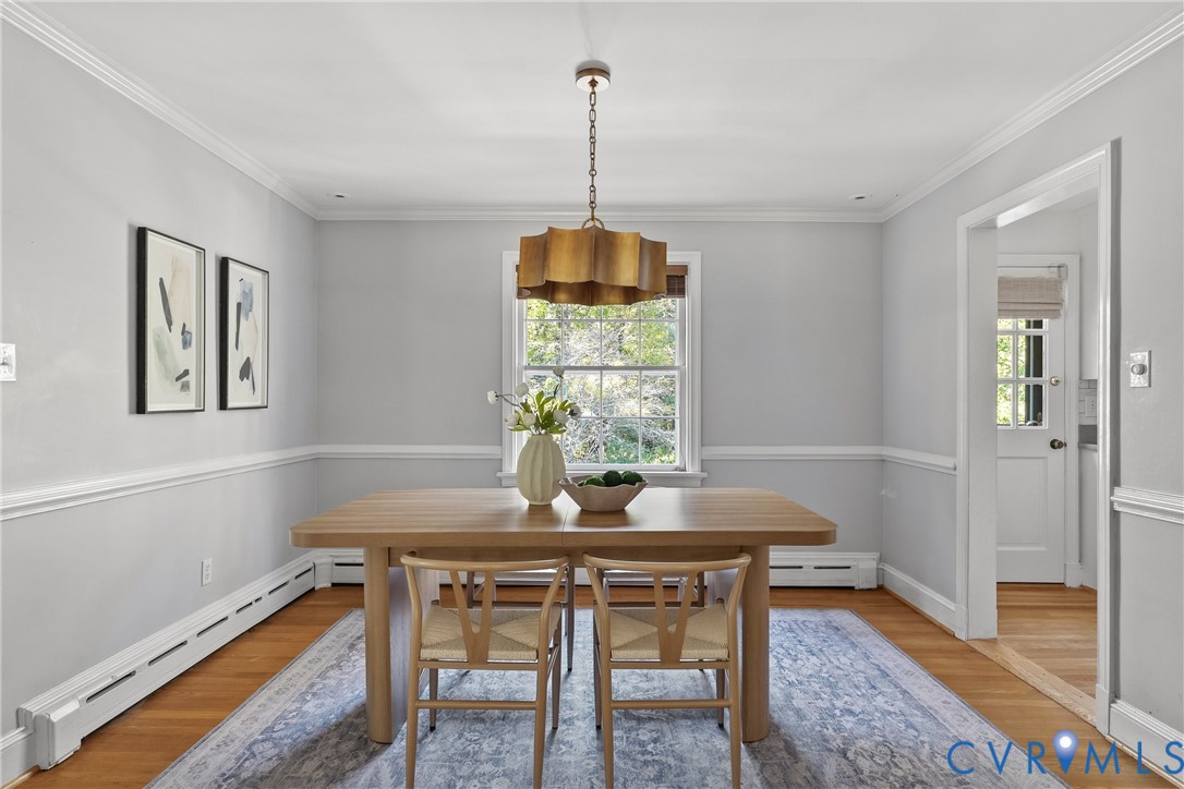 Dining area featuring decorative wall molding, hardwood flooring, and a multi-tiered metallic pendant light fixture