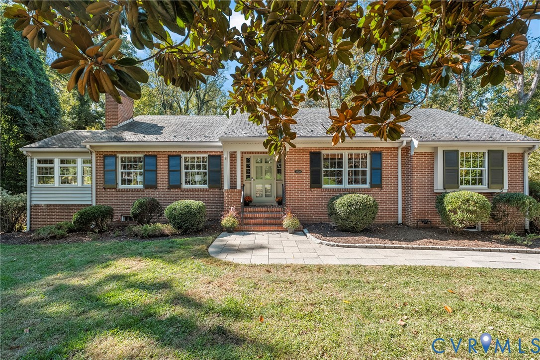 Single-story brick exterior featuring a stone-paved walkway, multi-pane windows with operable shutters, and a covered front entryway with brick steps Single-story brick exterior featuring a stone-paved walkway, multi-pane windows with operable shutters, and a covered front entryway with brick steps